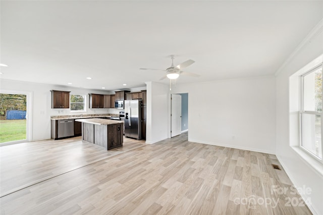 kitchen with a wealth of natural light, light hardwood / wood-style floors, a kitchen island, and appliances with stainless steel finishes