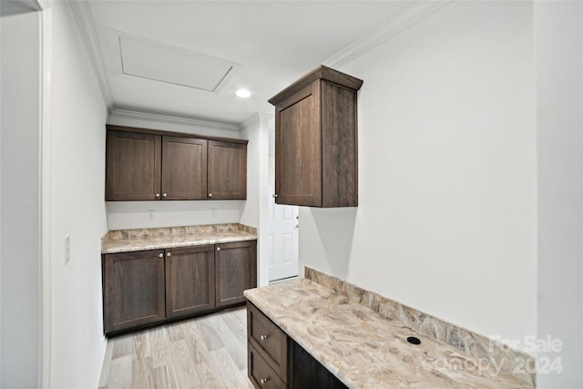 kitchen featuring dark brown cabinetry, light wood-type flooring, and ornamental molding