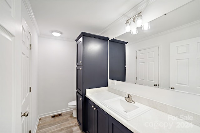 bathroom with toilet, wood-type flooring, crown molding, and vanity