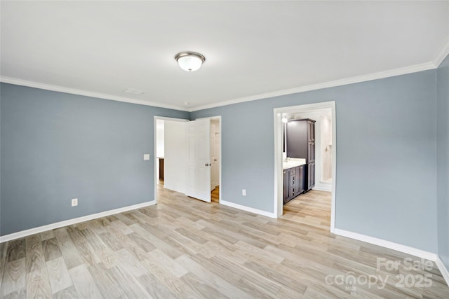 unfurnished bedroom with crown molding, light wood finished floors, ensuite bath, and baseboards