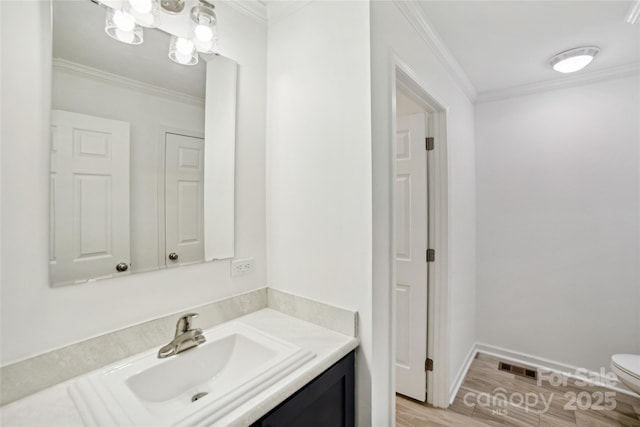 bathroom featuring toilet, wood finished floors, crown molding, and vanity