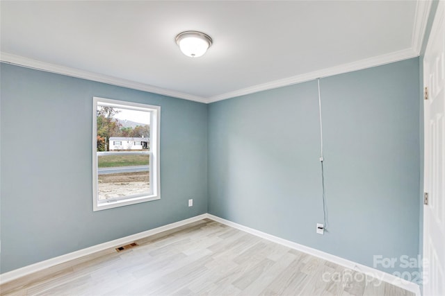 spare room with ornamental molding, visible vents, light wood-style flooring, and baseboards