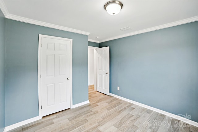 unfurnished bedroom featuring light wood finished floors, baseboards, and crown molding