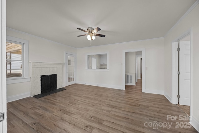 unfurnished living room with hardwood / wood-style floors, ceiling fan, crown molding, and a brick fireplace