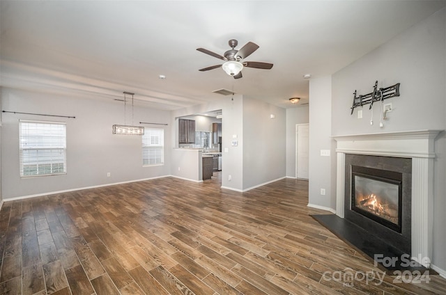 unfurnished living room with plenty of natural light, dark wood-type flooring, and ceiling fan