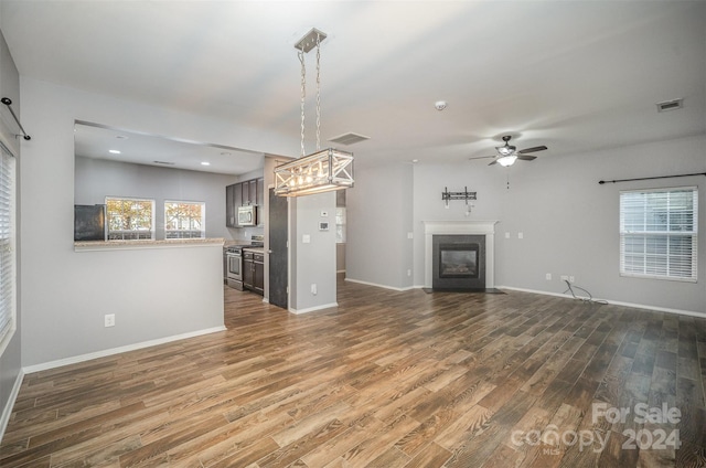 unfurnished living room with a wealth of natural light, dark hardwood / wood-style flooring, and ceiling fan