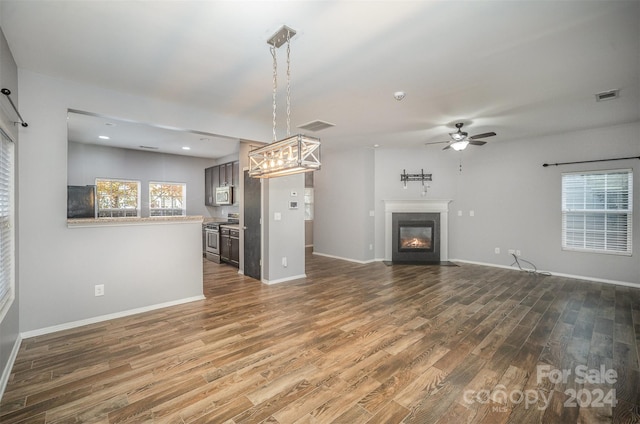 unfurnished living room with ceiling fan, plenty of natural light, and dark hardwood / wood-style floors