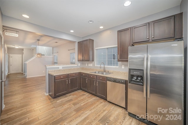 kitchen with kitchen peninsula, stainless steel appliances, sink, pendant lighting, and light hardwood / wood-style floors