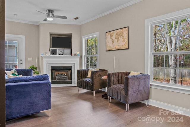 living area featuring ceiling fan, plenty of natural light, ornamental molding, and hardwood / wood-style flooring