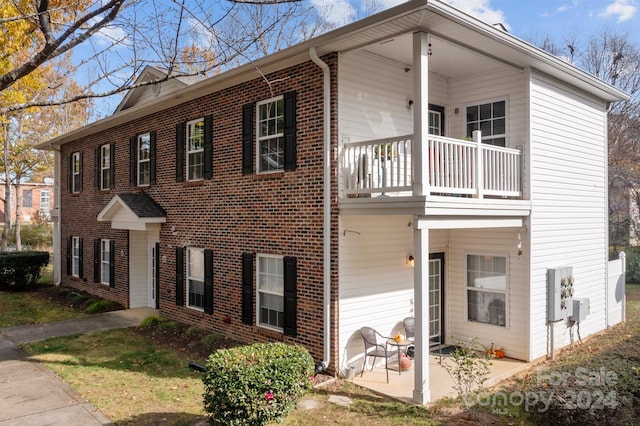 view of front of house featuring a balcony and a patio