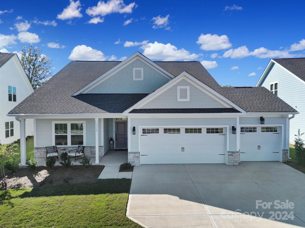 craftsman inspired home featuring a front yard, a porch, and a garage