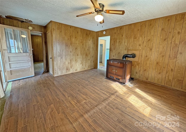 unfurnished room featuring a textured ceiling, wooden walls, hardwood / wood-style flooring, and ceiling fan