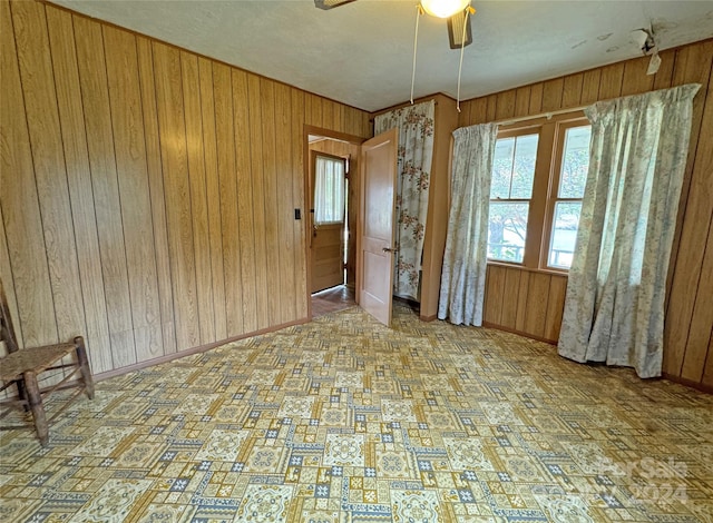 empty room featuring wood walls and ceiling fan