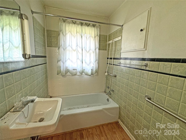 bathroom with tile walls, wood-type flooring, a healthy amount of sunlight, and sink