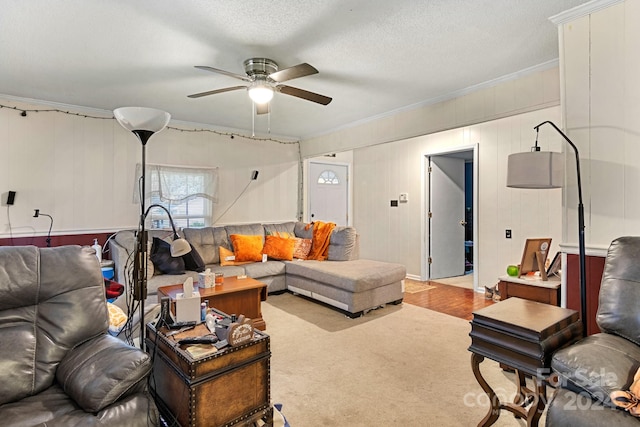 living room featuring ceiling fan, a textured ceiling, light carpet, and ornamental molding