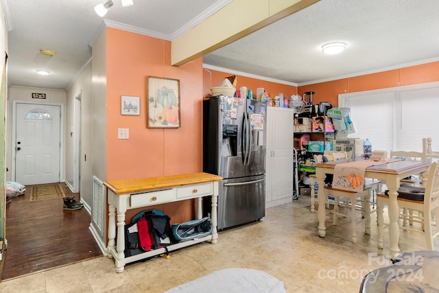 kitchen with ornamental molding, stainless steel refrigerator with ice dispenser, a textured ceiling, and light wood-type flooring