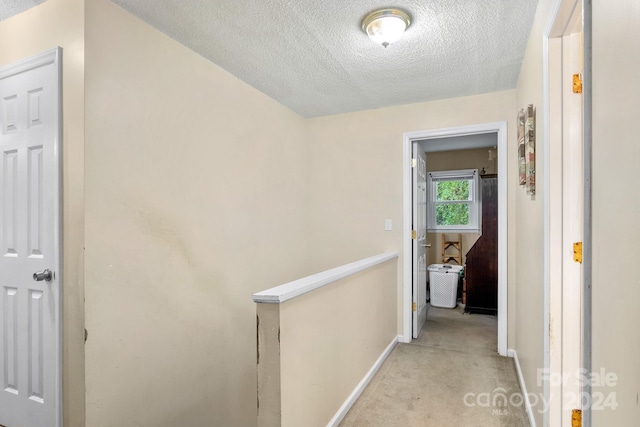 hall featuring a textured ceiling and light carpet