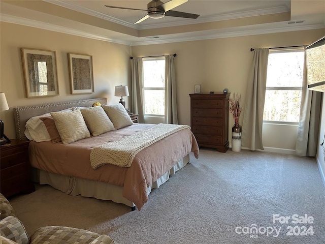 bedroom with ceiling fan, ornamental molding, light carpet, and a tray ceiling