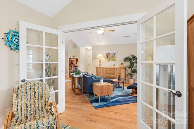 living area featuring hardwood / wood-style floors, vaulted ceiling, ceiling fan, and french doors