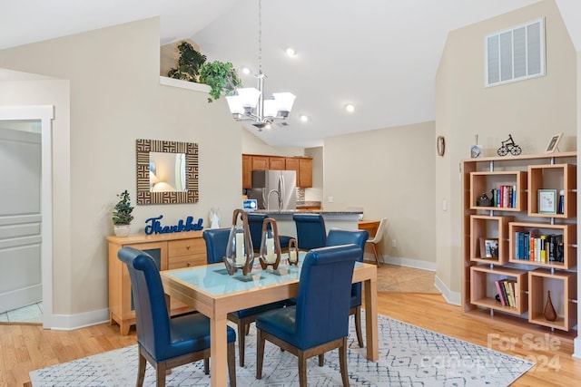 dining area featuring high vaulted ceiling, a chandelier, and light hardwood / wood-style floors