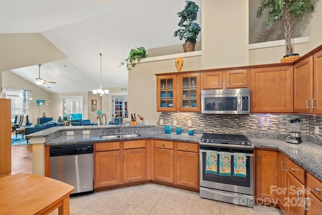 kitchen with high vaulted ceiling, stainless steel appliances, sink, and dark stone countertops