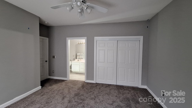 unfurnished bedroom with dark colored carpet, connected bathroom, ceiling fan, and a closet