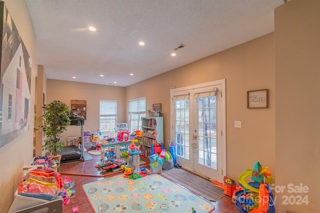 game room featuring wood-type flooring, a textured ceiling, and french doors