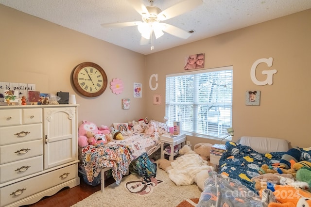 bedroom with a textured ceiling, ceiling fan, and dark wood-type flooring