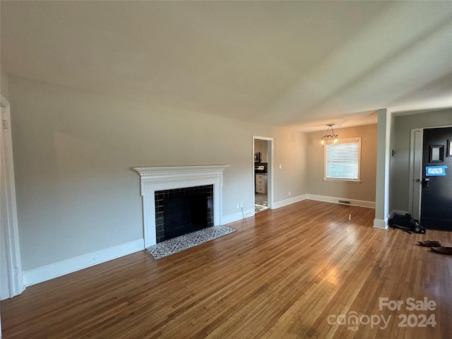 unfurnished living room with a tiled fireplace and hardwood / wood-style floors