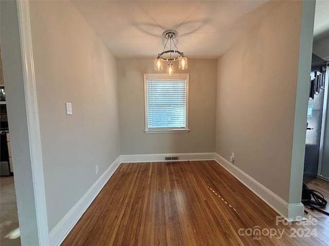 unfurnished dining area with hardwood / wood-style floors and a chandelier