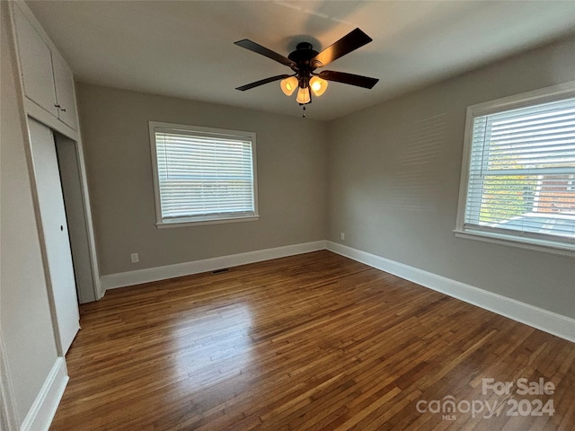 unfurnished bedroom with ceiling fan and dark wood-type flooring