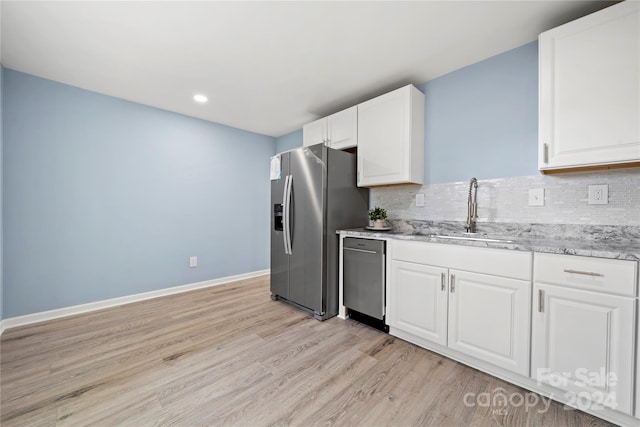 kitchen featuring appliances with stainless steel finishes, light wood-type flooring, backsplash, sink, and white cabinets