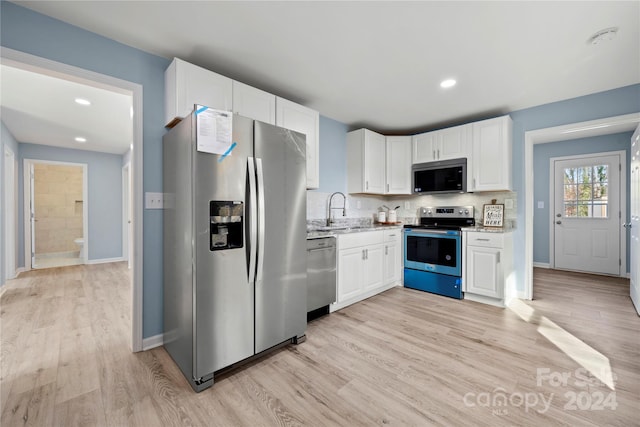 kitchen featuring sink, light hardwood / wood-style floors, light stone counters, white cabinetry, and stainless steel appliances