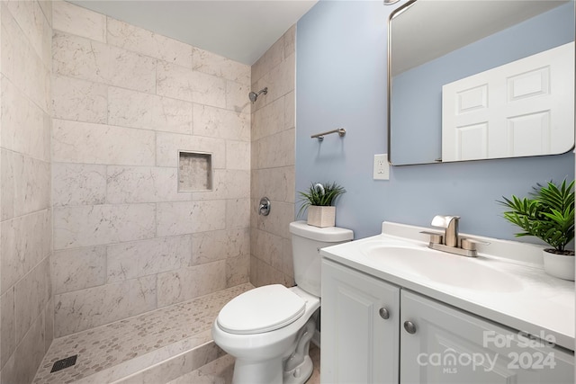 bathroom with tiled shower, vanity, and toilet