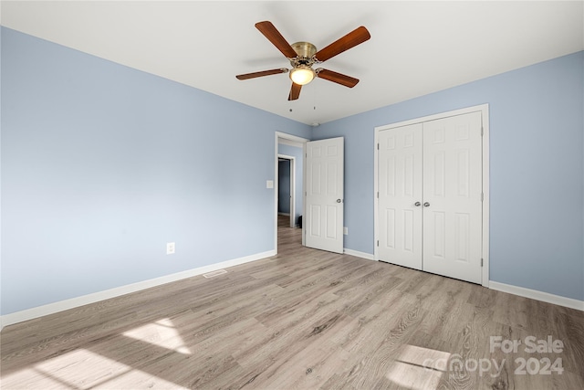 unfurnished bedroom featuring ceiling fan, a closet, and light hardwood / wood-style flooring