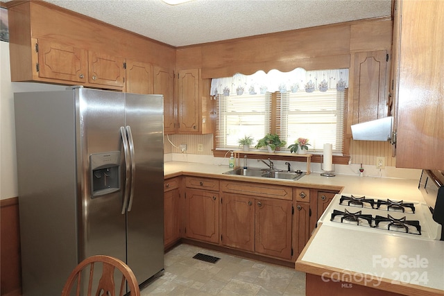 kitchen with white range with gas cooktop, extractor fan, a textured ceiling, stainless steel refrigerator with ice dispenser, and sink