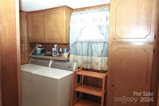 washroom featuring cabinets, washing machine and dryer, and a textured ceiling