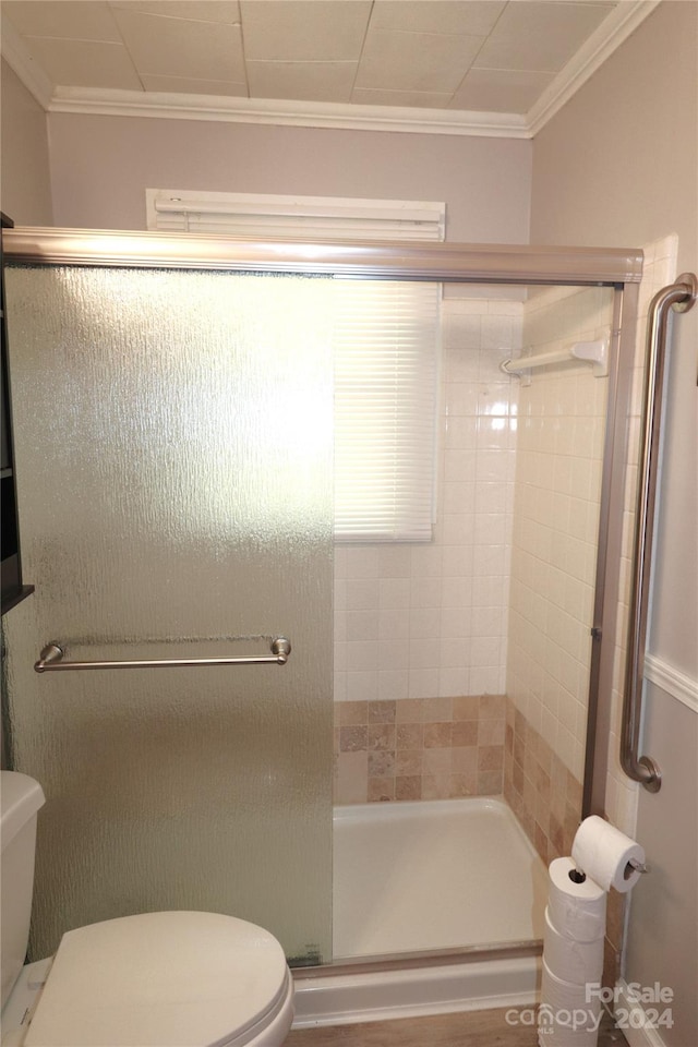 bathroom with a shower with door, toilet, and ornamental molding