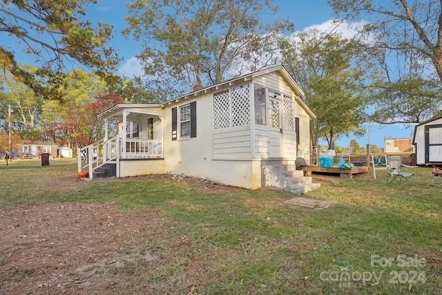 view of side of home with a porch and a yard