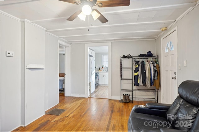 living area with hardwood / wood-style flooring, ceiling fan, and beam ceiling