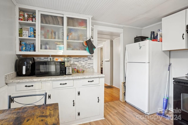 kitchen featuring white cabinetry, black appliances, light hardwood / wood-style flooring, crown molding, and decorative backsplash