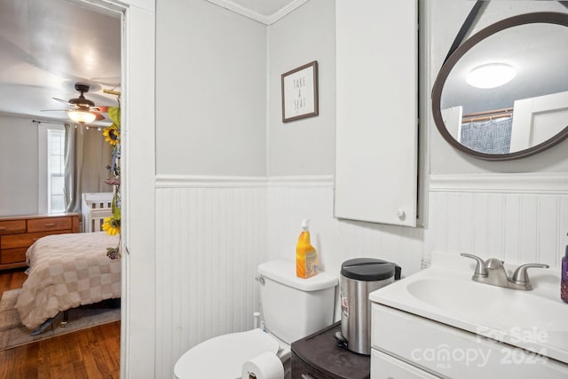 bathroom with ornamental molding, ceiling fan, wood-type flooring, vanity, and toilet