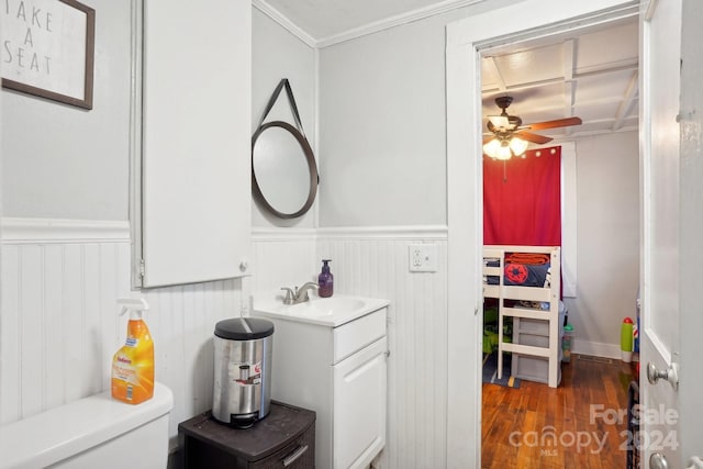 bathroom featuring wood-type flooring, toilet, ornamental molding, vanity, and ceiling fan