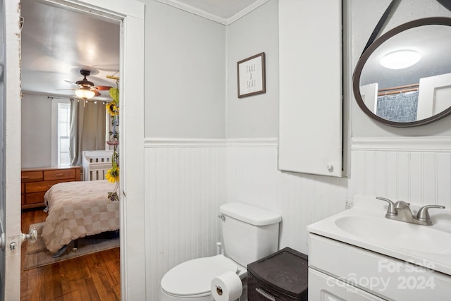 bathroom with toilet, hardwood / wood-style floors, vanity, ceiling fan, and crown molding