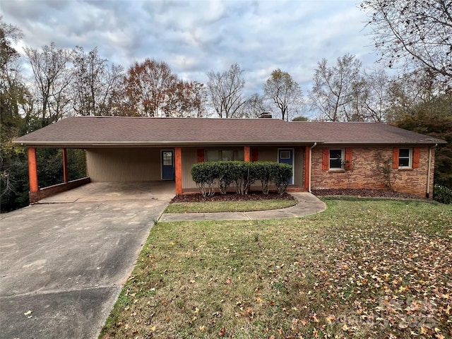 ranch-style home featuring concrete driveway, an attached carport, a chimney, and a front lawn