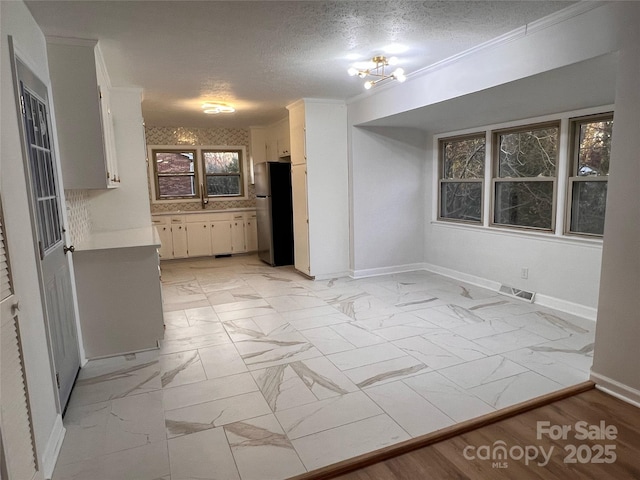 spare room featuring crown molding and a textured ceiling