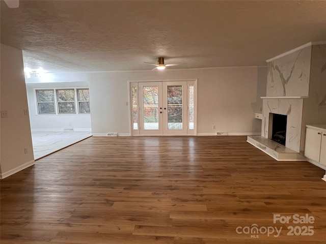 unfurnished living room with baseboards, dark wood-type flooring, a textured ceiling, a ceiling fan, and a premium fireplace