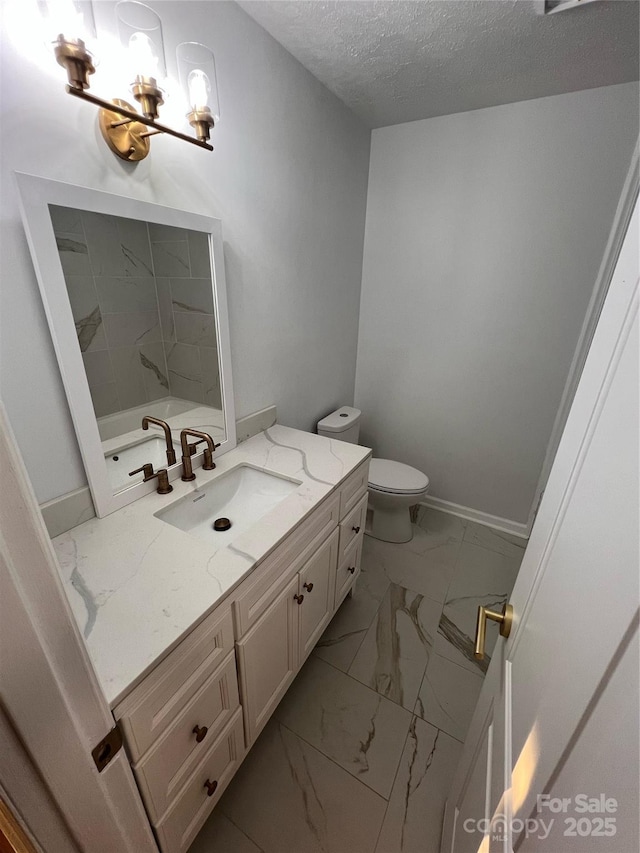 full bath with vanity, toilet, a textured ceiling, marble finish floor, and baseboards