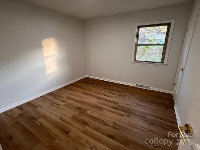 spare room featuring dark wood-style flooring, baseboards, and visible vents