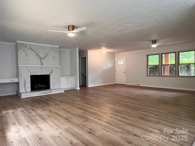 unfurnished living room with a textured ceiling, baseboards, a ceiling fan, and wood finished floors
